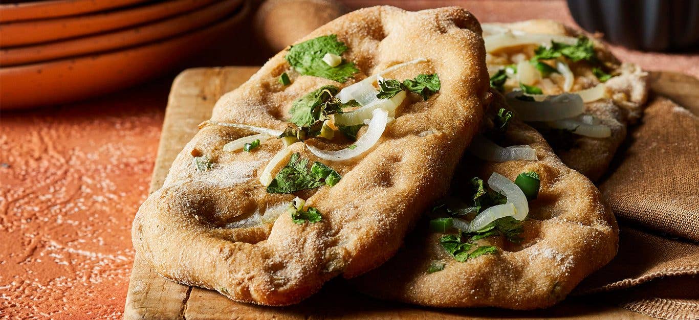 Garlic-Jalapeño Naan with fresh cilantro on a wooden cutting board