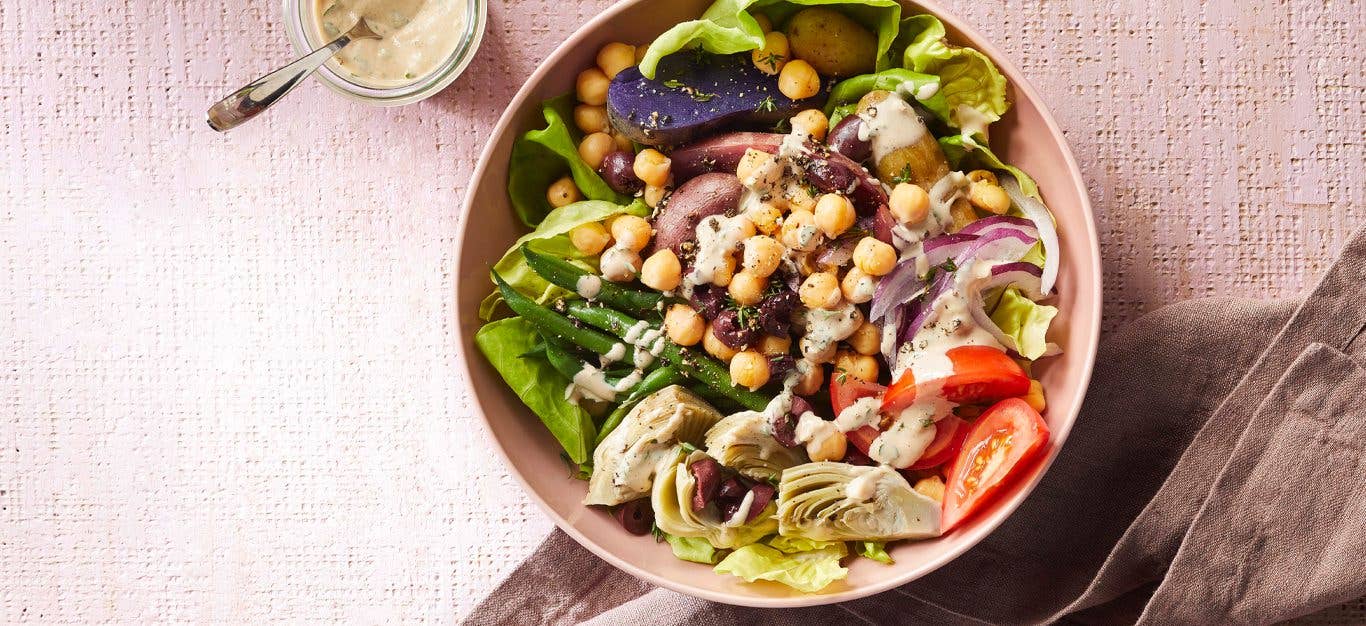 Vegan Niçoise Salad Bowls in a light pink dish with a small bowl of tahini dressing